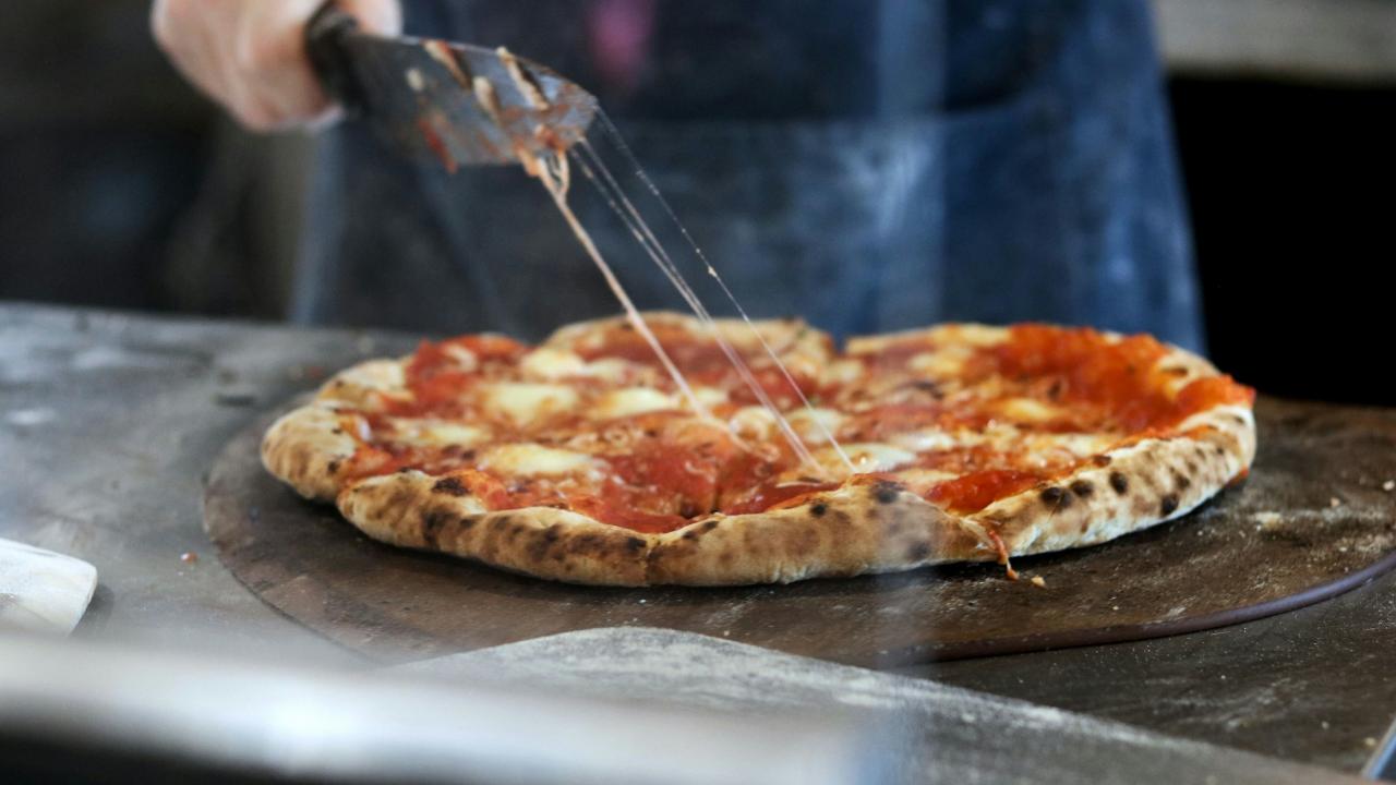 picture of pizza being cut with knife